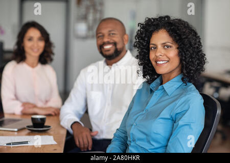 Diverse businesspeople smiling while sitting together at an office table Stock Photo