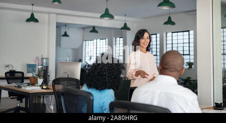 Smiling businesswoman meeting with her diverse team in an office Stock Photo