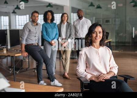 Young businesswoman smiling with colleagues standing in the background Stock Photo