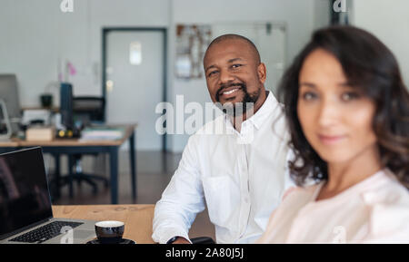 Smiling businessman sitting with a colleague in an office Stock Photo