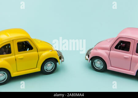 Simply design with two yellow pink vintage retro toy car isolated on blue pastel colorful background. Automobile and transportation symbol. City traffic delivery concept. Copy space for text Stock Photo