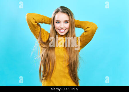 Portrait of a beautiful girl, in a yellow hat and sweater, looking at the camera and smiling cute. Stock Photo