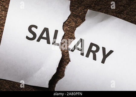 Sheet with the words salary, torn in half. Concept on the financial crisis. There will be no salary Stock Photo