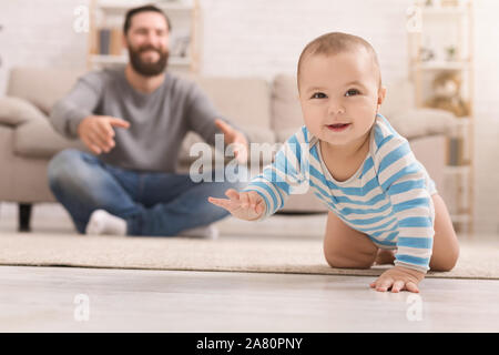 Adorable baby boy crawling on floor with dad Stock Photo