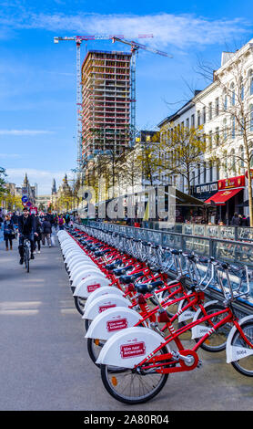 Line of city bikes for rental - 'Velo Antwerpen' - and Antwerp Tower building reconstruction - Antwerp, Belgium. Stock Photo