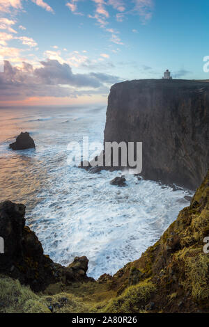 Cape Dyrholaey lighthouse in southern Iceland. Cloudy sunset from the cliff. Strong waves. Stock Photo