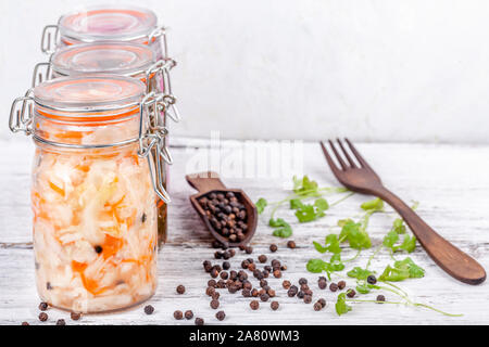 Homemade marinated sauerkraut sour in glass jars on rustic wooden kitchen table Stock Photo