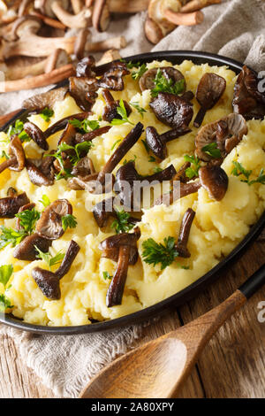 Roasted mushrooms with a side dish of potatoes and parsley close-up in a plate on the table. vertical Stock Photo