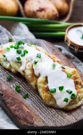 Fresh homemade pan-fried potato pancakes latkes on rustic wooden cutting board. Traditional jewish food for Hannukah celebration. Selective focus. Stock Photo