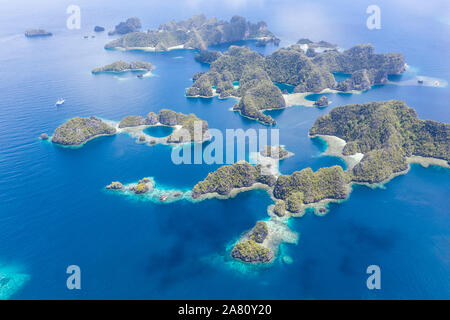 Highly eroded limestone islands rise from the beautiful, tropical seascape in Raja Ampat, Indonesia. This remote region is known for its biodiversity. Stock Photo
