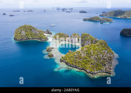 Highly eroded limestone islands rise from the beautiful, tropical seascape in Raja Ampat, Indonesia. This remote region is known for its biodiversity. Stock Photo
