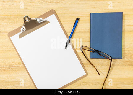 Flat lay, top view office table desk. Workspace with blank clip board, pen, glasses and diary on wooden table. Mock up, copy space. Working concept Stock Photo