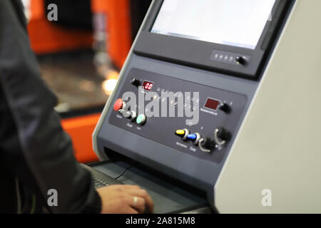 Operator working with a control panel of CNC laser metal cutter. Selective focus. Stock Photo