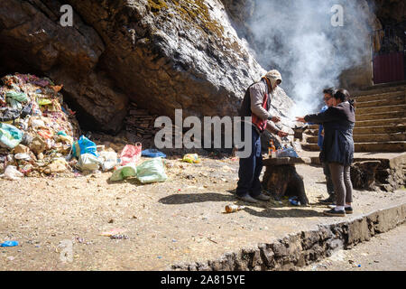 Shaman performing an offering ritual for a local couple at the Cave of the Virgin of Lourdes near Copacabana, Bolivia Stock Photo