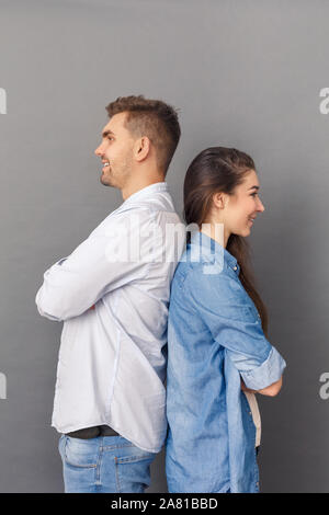 Relationship Concept. Young couple studio standing back to back isolated on grey smiling joyful Stock Photo