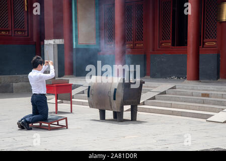 Beijing, China, June 8 2018 : Religious man praying at the Lama temple which is the biggest Tibetan Buddhist temple in Beijing, China Stock Photo