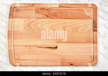 Large empty wooden kitchen cutting board made of birch wood, lies on a marble countertop. Stock Photo