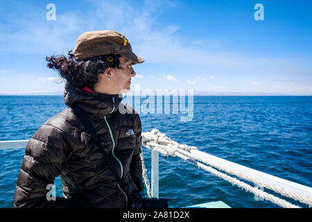Young woman on the upper deck of a tourist boat enjoying a ride on the Lake Titicaca, Bolivia Stock Photo