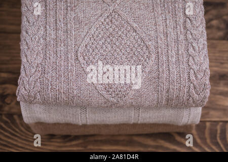 Stack of cozy knitted sweaters on a wooden table. Retro style. Warm concept, toned Stock Photo