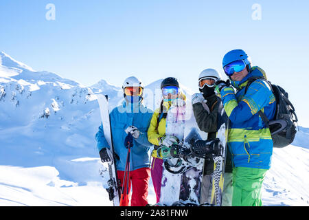 Photo of four sportsmen wearing helmet and holding snowboards at snow resort on winter day Stock Photo