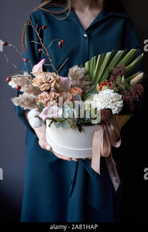 Female hands holding a box with a vintage bouquet on a dark background, selective focus Stock Photo