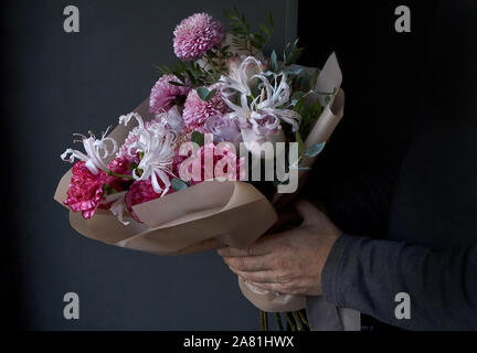Male hands holding a bouquet decorated in vintage style on a dark background, selective focus Stock Photo