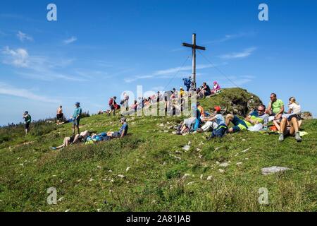 Mountain hikers rest at the summit cross of the Hoher Ifen mountain, near Hirschegg, Kleinwalsertal, Vorarlberg, Allgauer Alps, Austria Stock Photo