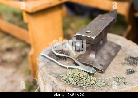 An anvil with tools and lot of rings for chain mail. Close up view, shallow depth of field Stock Photo