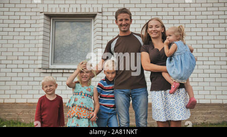 A large family with four children in front of their own home. Stock Photo