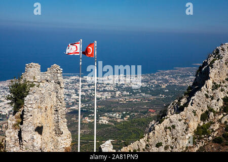 Flags of the Turkish Republic of Northern Cyprus and Turkey fly over the Gatehouse, Saint Hilarion Castle, Northern Cyprus: view over Kyrenia beyond Stock Photo