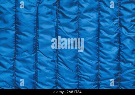Shiny clothing background. Dark blue background from quilted material. Stock Photo