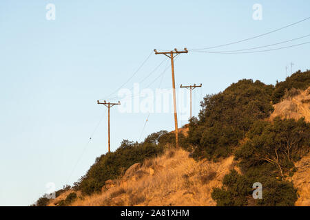 Old rural power lines above dry brush hillside near Los Angeles and Ventura County in Southern California.
