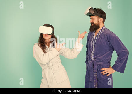 Future is closer than you think. Man and woman explore VR at home. VR technology and future. VR communication. Exciting impressions. Couple in bathrobes wear VR glasses. Gaming and entertainment. Stock Photo