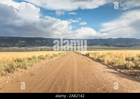 Long straight dirt road in Utah with dramatic clouds Stock Photo