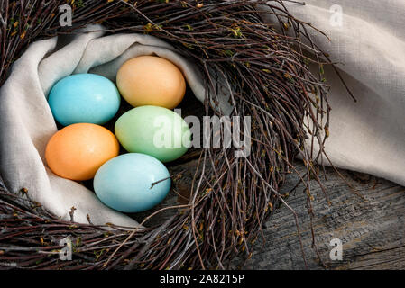 Easter still life. Multicolored eggs in a nest on a wooden surface. Stock Photo