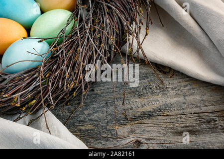 Easter still life. Multicolored eggs in a nest on a wooden surface. Stock Photo