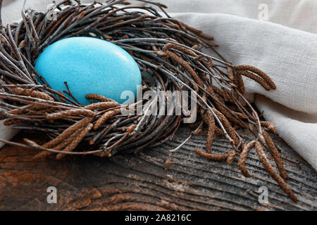Easter still life. Blue egg in a nest on a wooden surface. Stock Photo