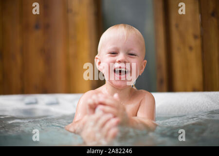 Laughing toddler playing in a spa bath. Stock Photo