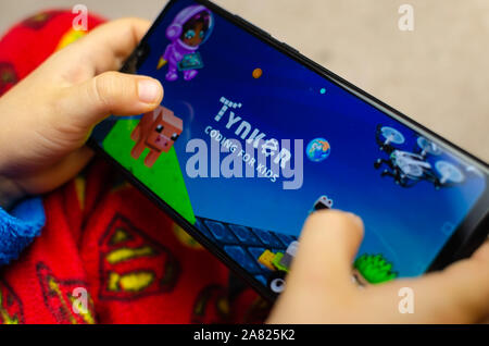 Tynker app logo on the smartphone screen hold in child's hands. Stock Photo