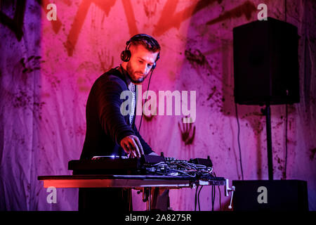 DJ plays live set and mixing music on turntable console at stage in the night club. Disc Jokey Hands on a sound mixer station at club party. DJ mixer Stock Photo