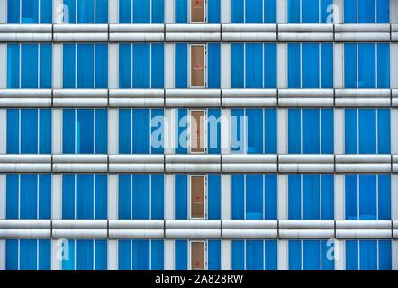 Exterior of modern building with geometric metal cladding and blue glass windows as architectural background Stock Photo