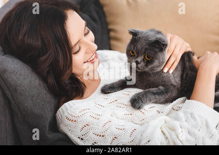 beautiful woman lying on sofa with scottish fold cat Stock Photo