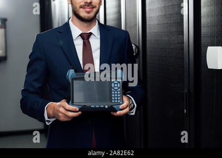 cropped view of happy businessman holding reflectometer in server room Stock Photo