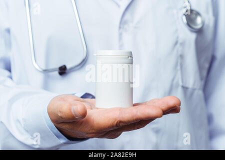 doctor holding bottle of pills on white background. The concept of medicine, pharmacology, healthcare. Stock Photo