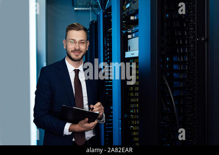 happy businessman in glasses holding clipboard in data center Stock Photo
