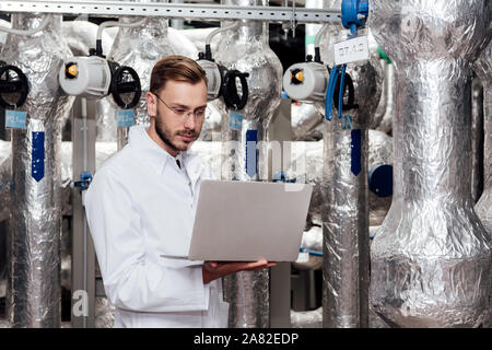handsome bearded engineer in white coat holding laptop Stock Photo