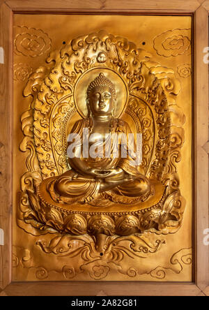 Da Nang, Vietnam - March 10, 2019: Chua An Long Chinese Buddhist Temple. Closeup of framed gold plated image of sitting Buddha. Stock Photo