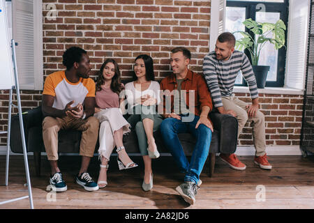 young multicultural businesspeople sitting on sofa and discussing business ideas Stock Photo