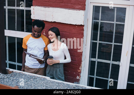 young african american businessman showing documents to attractive colleague holding coffee to go Stock Photo