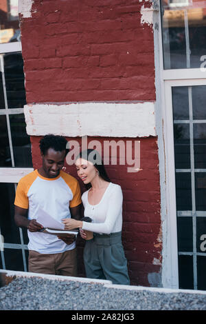 smiling african american businessman showing documents to attractive colleague holding coffee to go Stock Photo